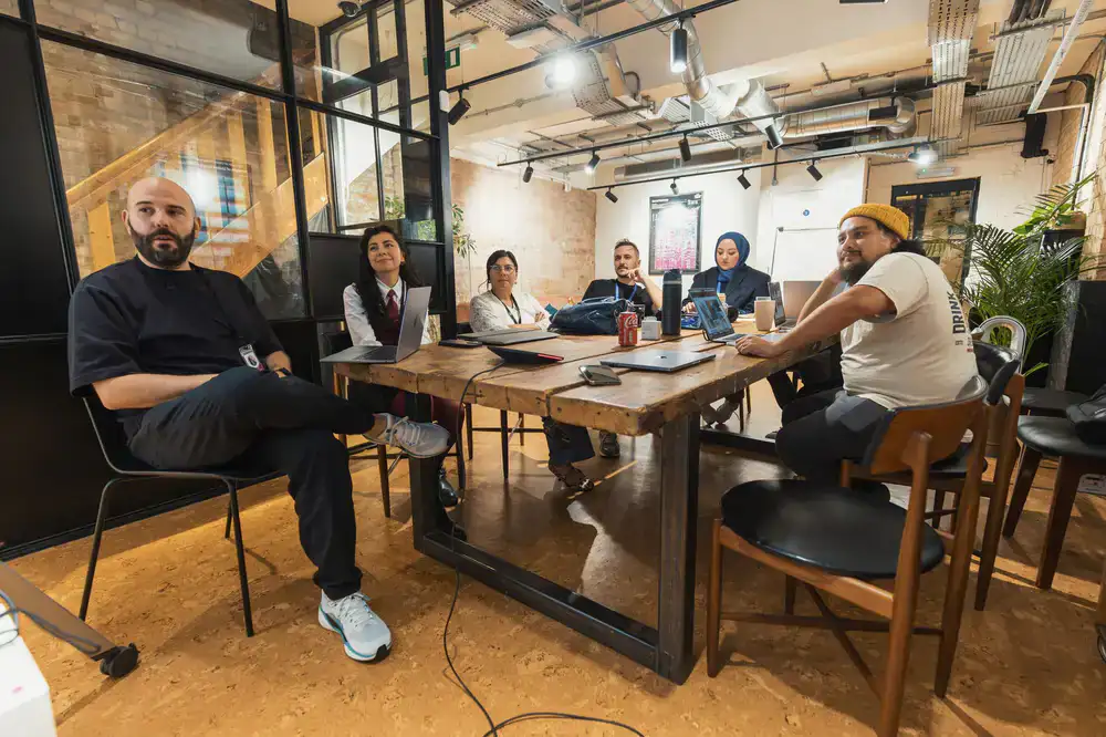 A group of people smiling around a large work table covered in plants